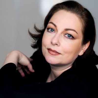 Dorothea Röschmann wearing a long sleeve black top looking at the camera smiling